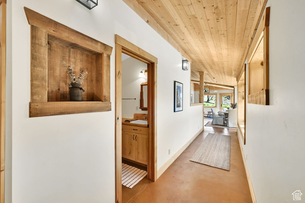 Corridor with a sink, wood ceiling, baseboards, and finished concrete floors