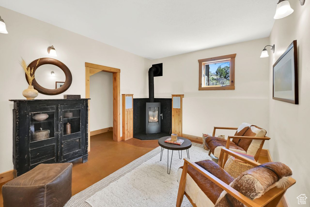 Living area with baseboards, a wood stove, and finished concrete floors