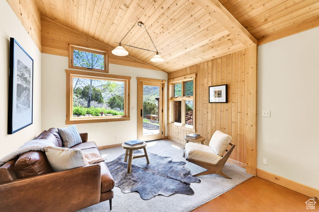 Living area featuring baseboards, wood walls, vaulted ceiling, and wooden ceiling