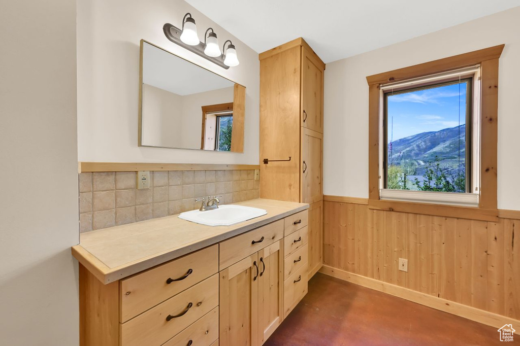 Bathroom featuring decorative backsplash, wood walls, a wainscoted wall, vanity, and concrete floors