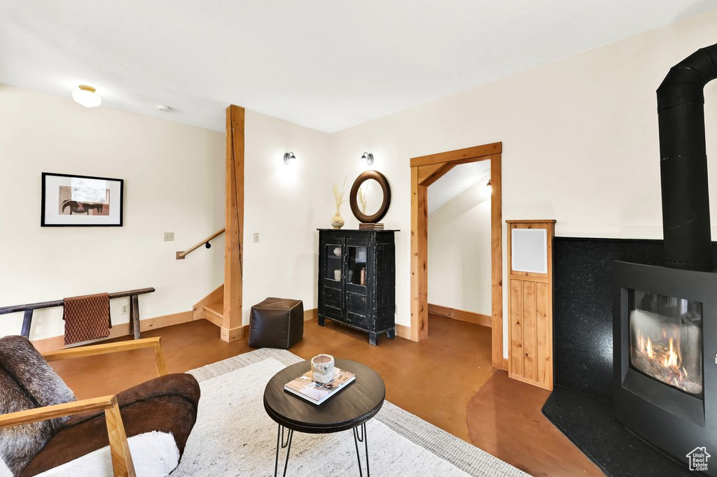 Living room with baseboards, a wood stove, stairs, and finished concrete floors