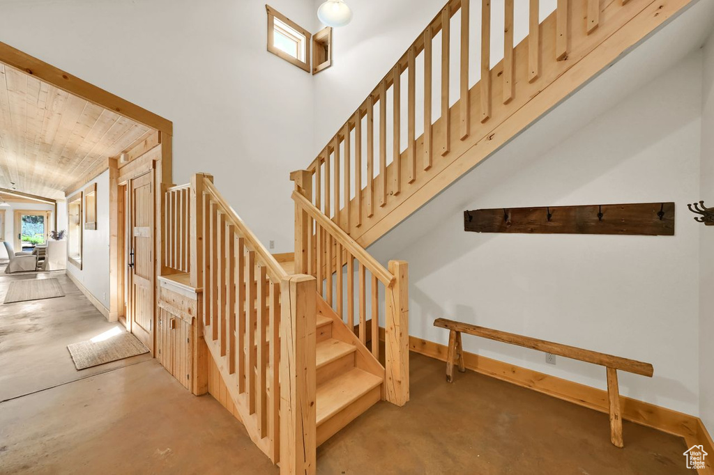 Staircase featuring baseboards, concrete flooring, and wooden ceiling