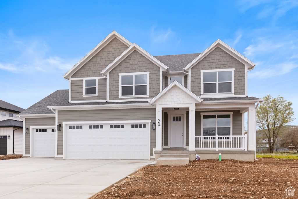 View of front of home with an attached garage, roof with shingles, covered porch, and driveway