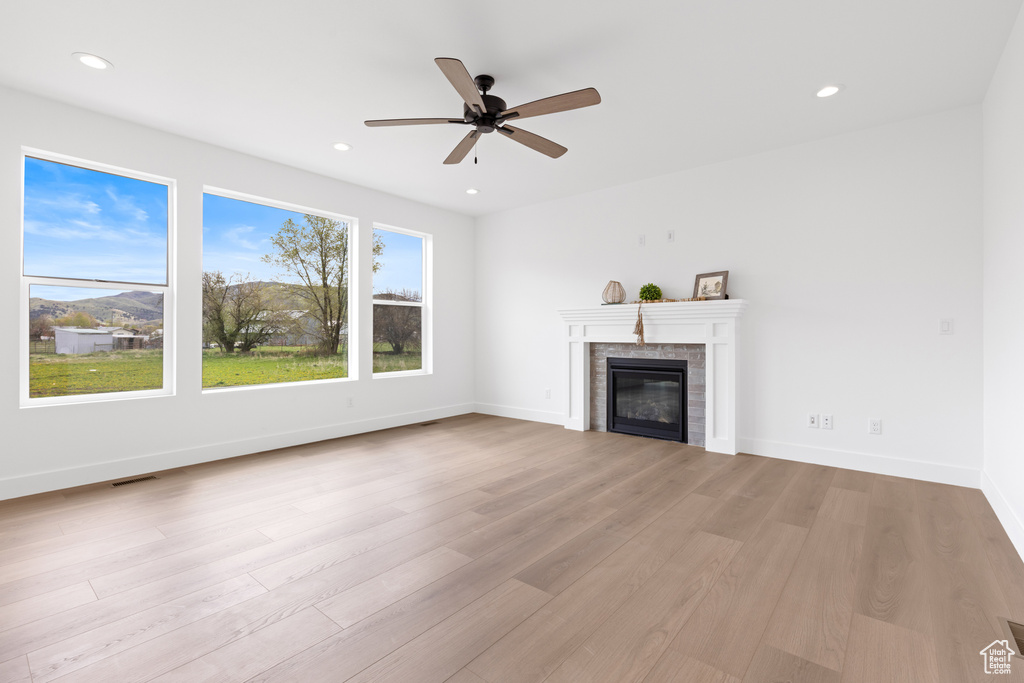 Unfurnished living room featuring recessed lighting, a glass covered fireplace, ceiling fan, and wood finished floors