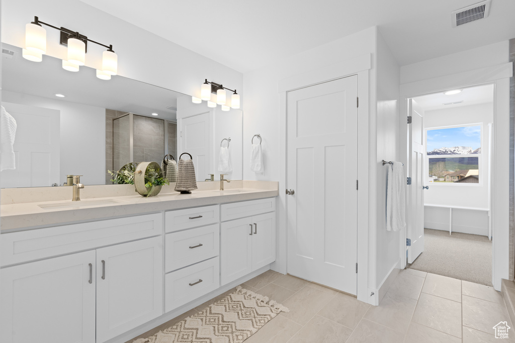 Bathroom with double vanity, visible vents, a shower stall, and a sink