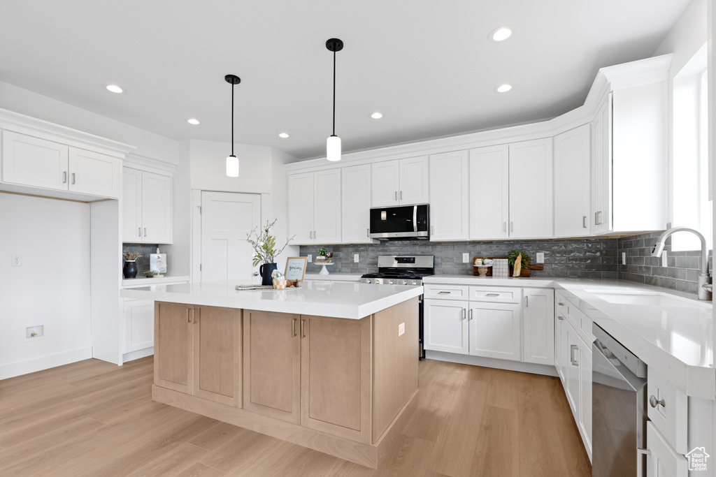 Kitchen with a sink, a center island, stainless steel appliances, and light wood-type flooring