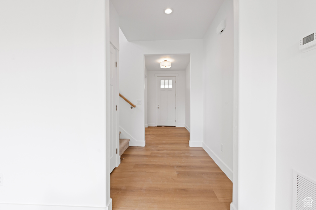 Corridor featuring recessed lighting, baseboards, light wood-style flooring, and stairway