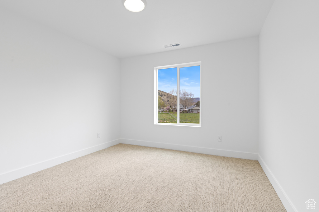 Empty room featuring visible vents, baseboards, and light colored carpet