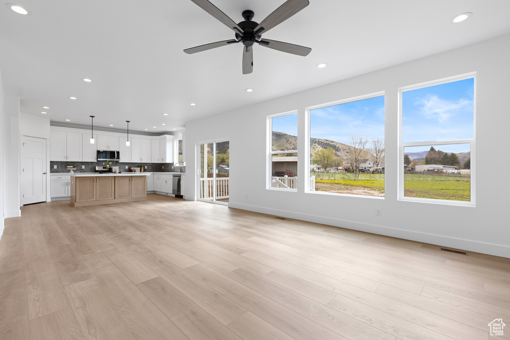 Unfurnished living room with recessed lighting, ceiling fan, baseboards, and light wood-type flooring