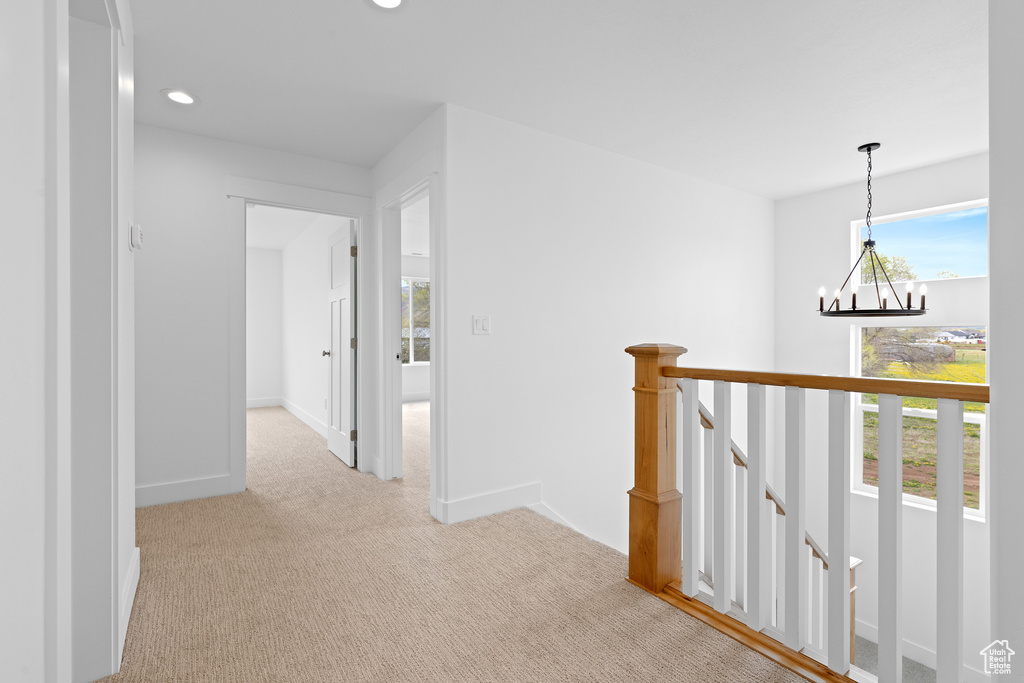 Hallway with light colored carpet, an inviting chandelier, recessed lighting, baseboards, and an upstairs landing