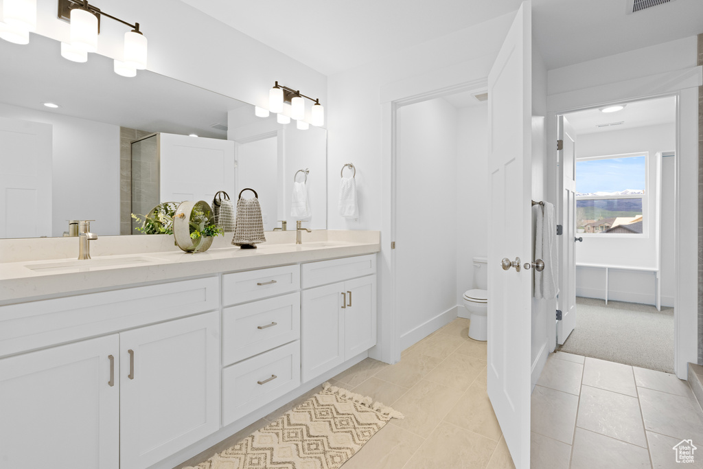 Bathroom with double vanity, visible vents, an enclosed shower, a sink, and toilet