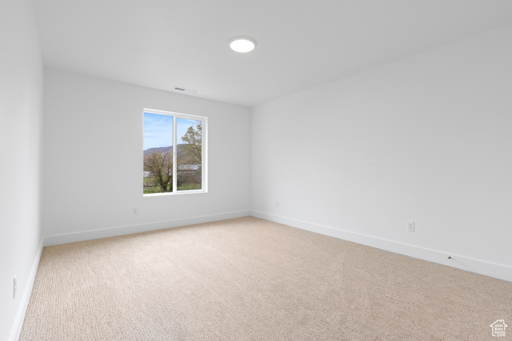 Carpeted empty room featuring baseboards and visible vents
