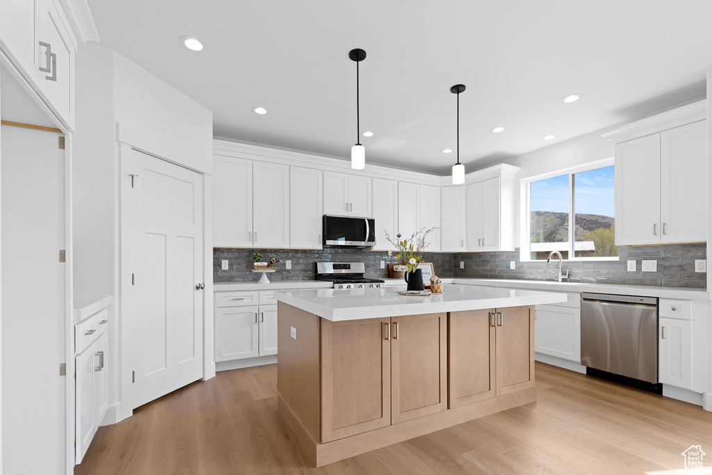 Kitchen with light wood-style floors, tasteful backsplash, and stainless steel appliances