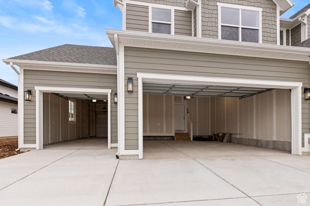 Exterior space featuring a garage, concrete driveway, and roof with shingles
