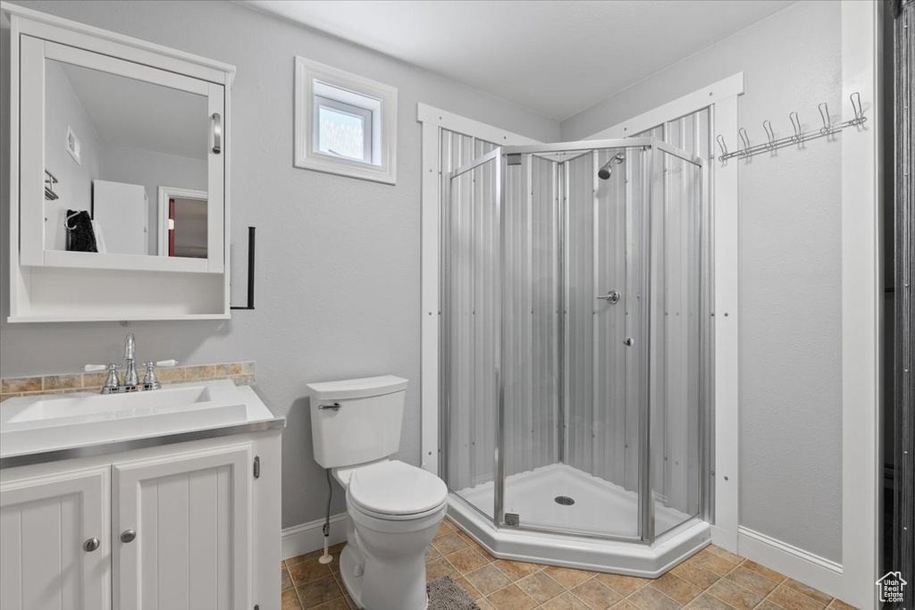 Bathroom with baseboards, vanity, toilet, and a shower stall