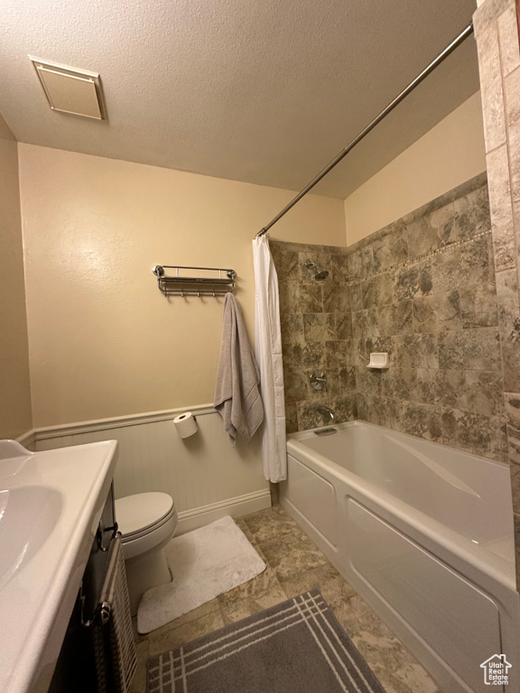 Bathroom with vanity, toilet, a textured ceiling, and shower / tub combo with curtain