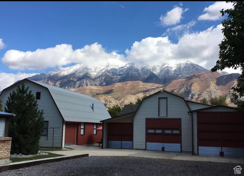 View of front facade with a detached garage, an outbuilding, a mountain view, and a gambrel roof