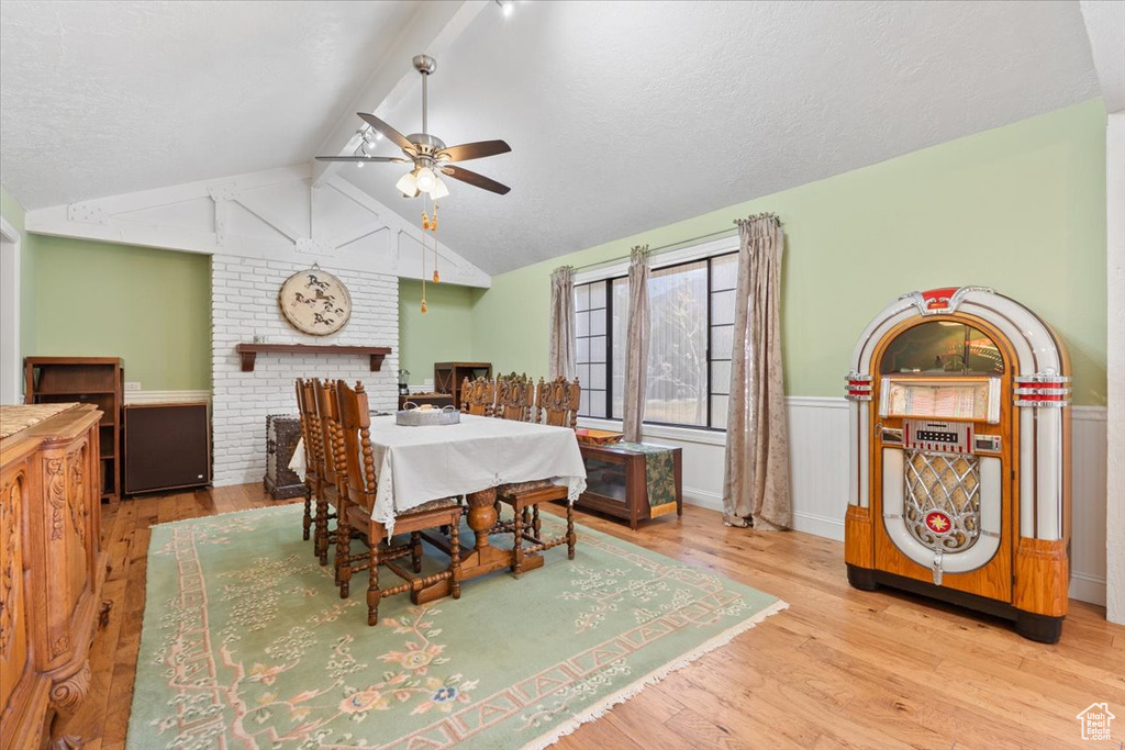 Dining area featuring vaulted ceiling with beams, ceiling fan, wainscoting, and wood finished floors