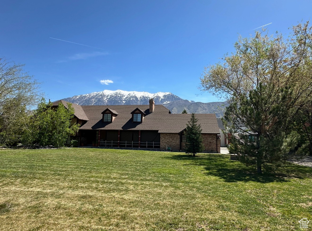 Exterior space with a lawn, a mountain view, a chimney, and brick siding