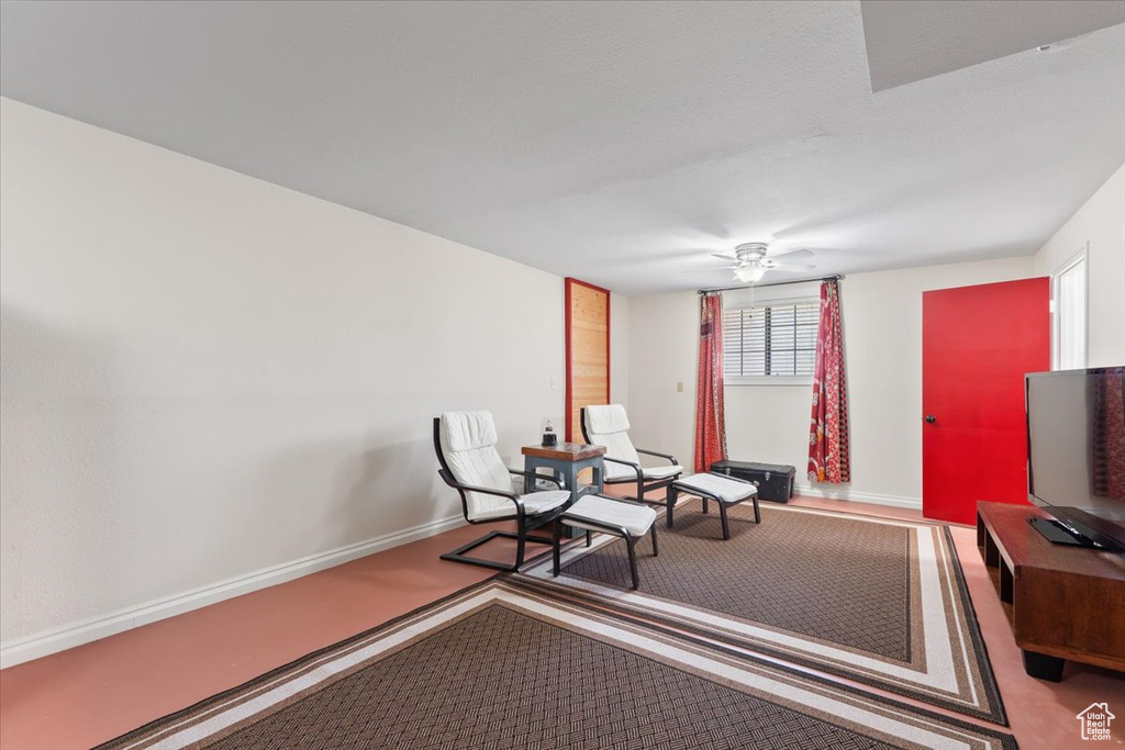 Living area featuring carpet flooring, ceiling fan, and baseboards