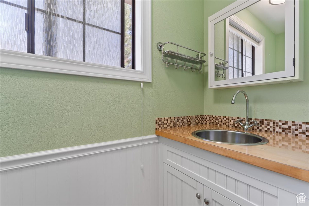 Interior space with a textured wall, a sink, and a wainscoted wall