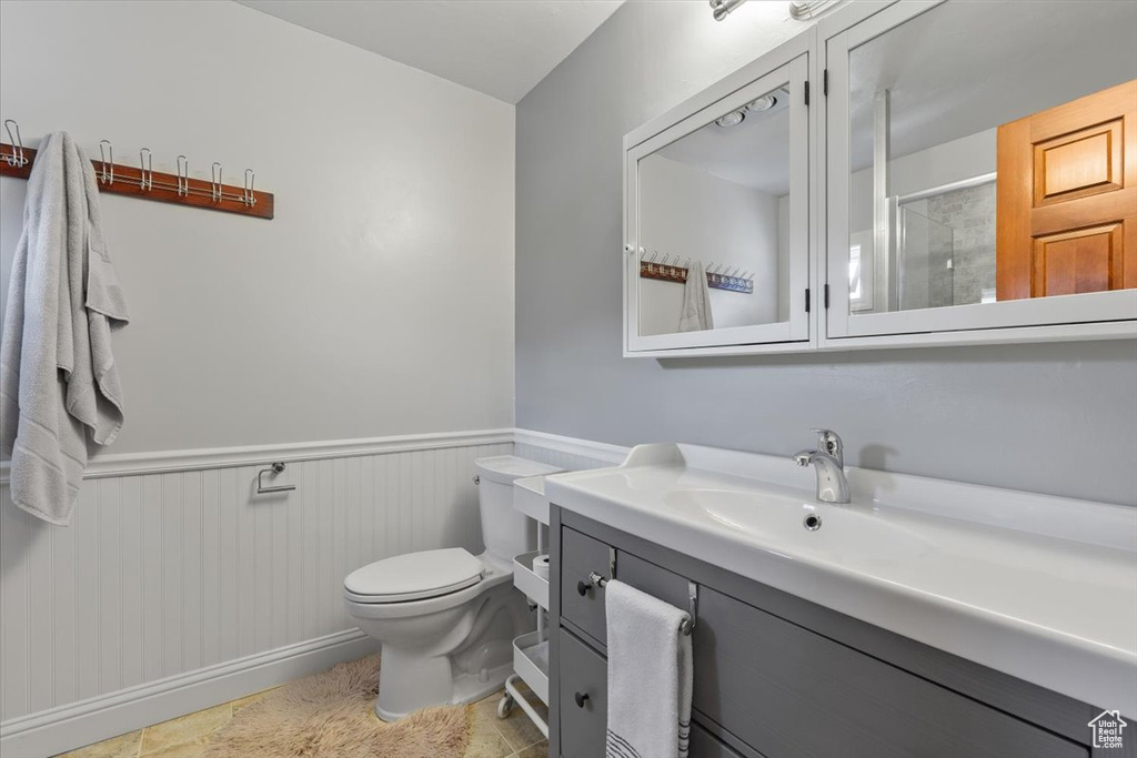Bathroom featuring vanity, wainscoting, toilet, and a shower