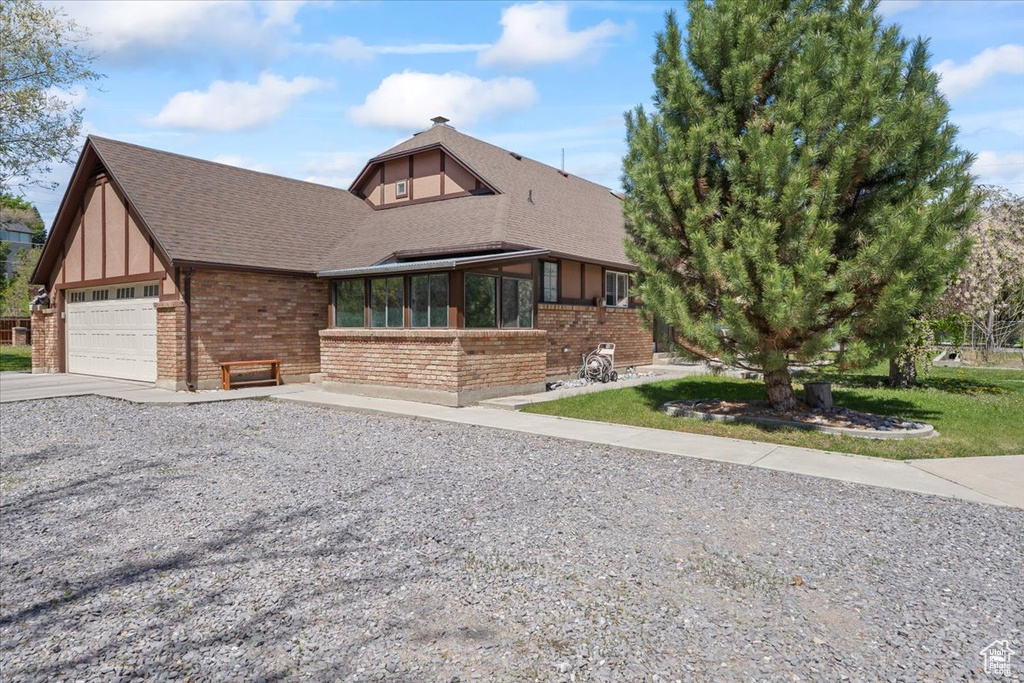 View of front facade with roof with shingles, brick siding, a garage, a sunroom, and concrete driveway