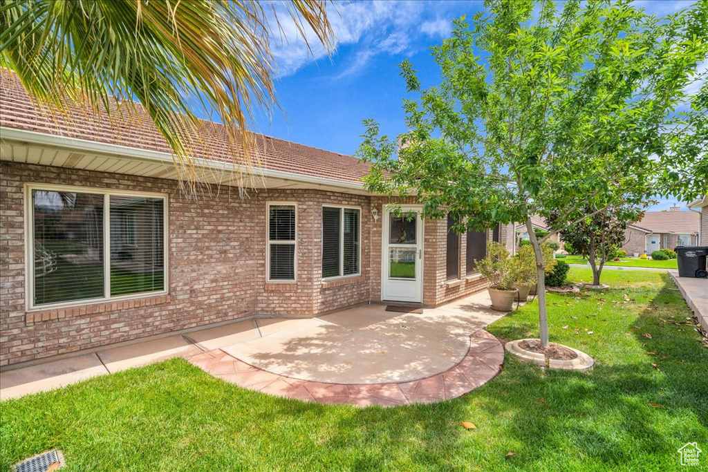 Rear view of house with a yard, a patio area, and brick siding