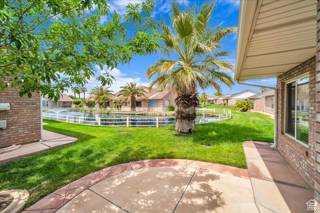 View of yard with fence, a water view, and a patio area