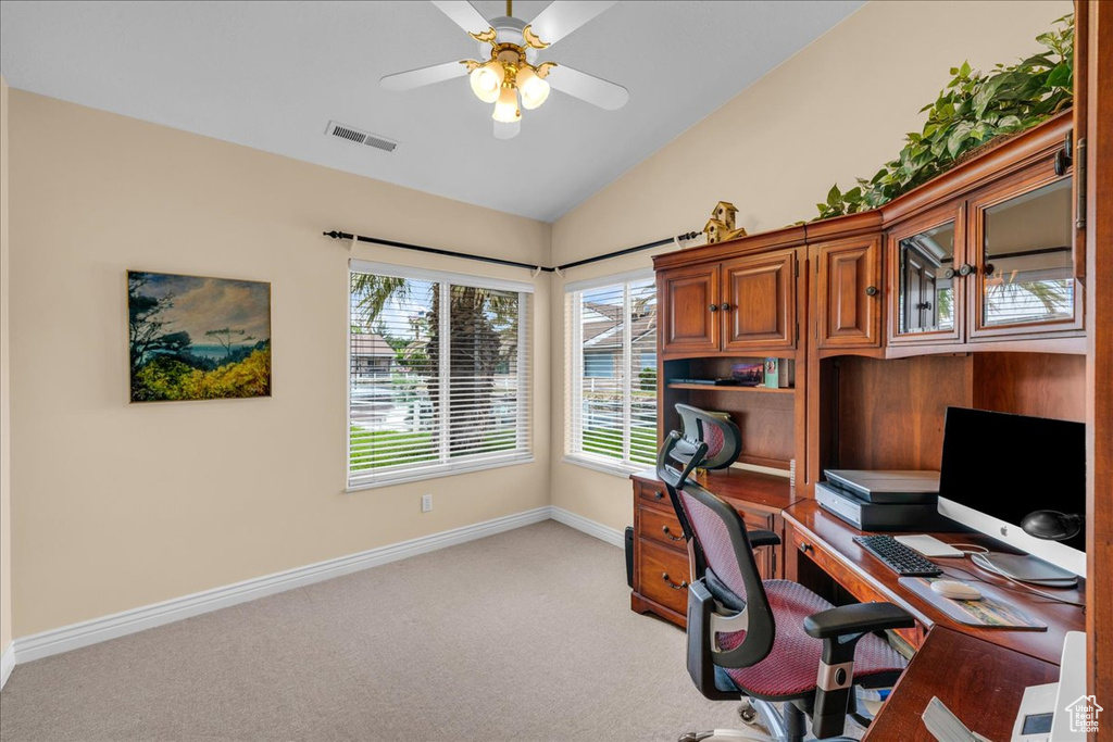 Office space with ceiling fan, visible vents, baseboards, lofted ceiling, and light carpet