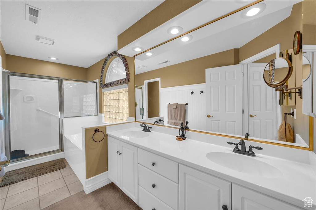 Full bathroom with double vanity, visible vents, a sink, and a stall shower