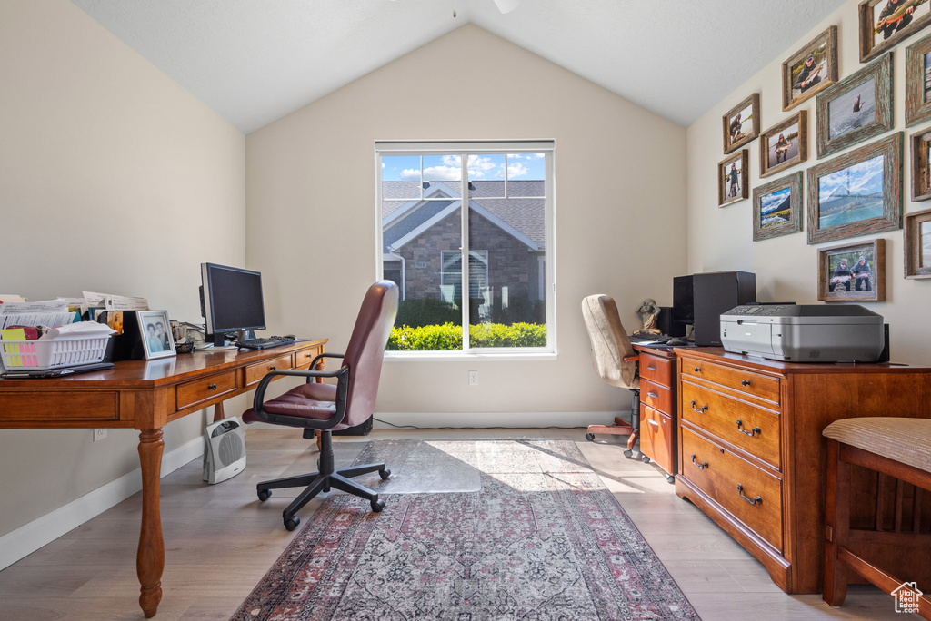 Office area featuring baseboards, ceiling fan, vaulted ceiling, and light wood finished floors