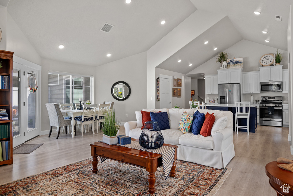 Living area with recessed lighting, high vaulted ceiling, light wood finished floors, and visible vents