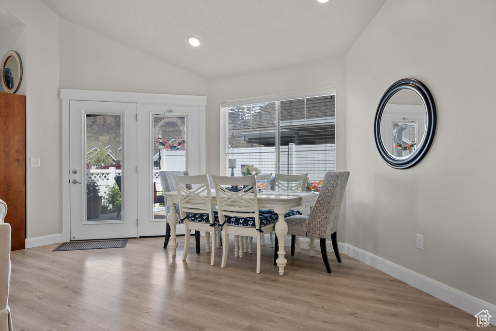 Dining space featuring baseboards, vaulted ceiling, and light wood-style flooring