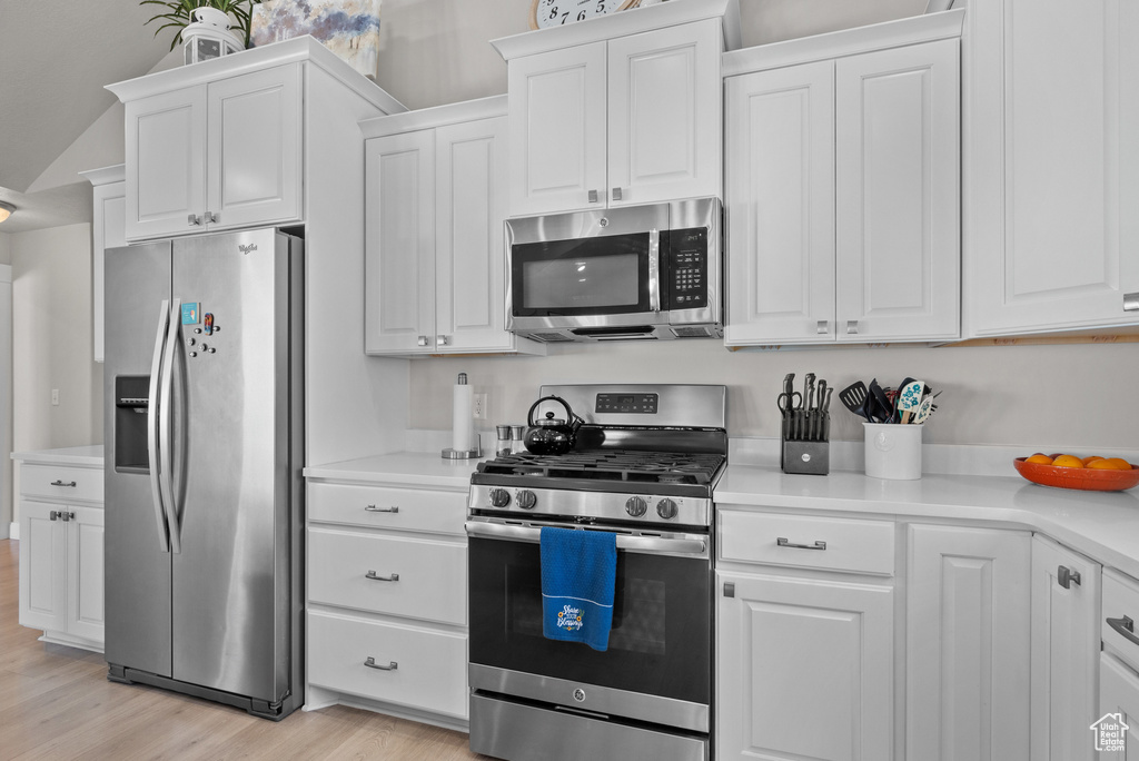 Kitchen featuring light countertops, stainless steel appliances, white cabinetry, and light wood finished floors