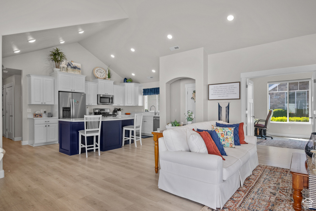 Living area featuring recessed lighting, high vaulted ceiling, visible vents, and light wood-style floors