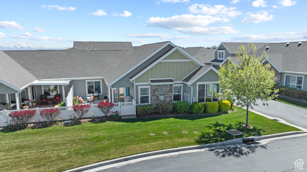 Exterior space with board and batten siding, fence private yard, stone siding, and a front lawn