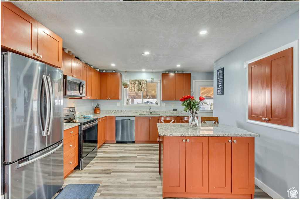 Kitchen with light stone countertops, a sink, light wood-style flooring, stainless steel appliances, and recessed lighting