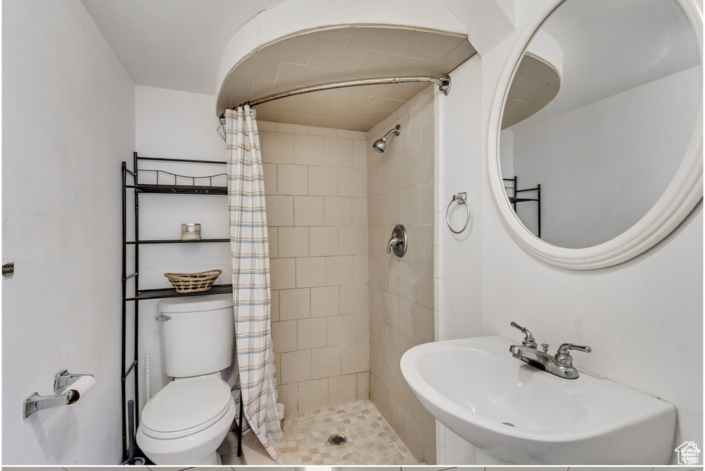 Bathroom featuring toilet, a shower stall, and a sink