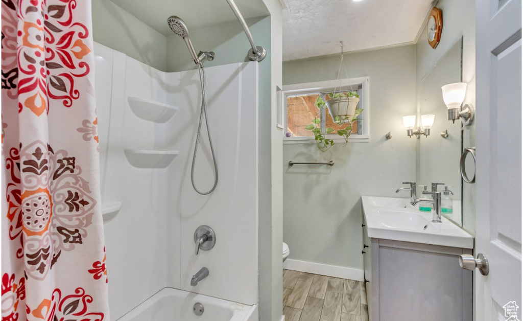 Bathroom featuring vanity, baseboards, shower / bath combo, and toilet