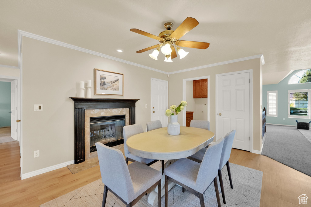 Dining area with light wood-style floors, baseboards, ceiling fan, and ornamental molding