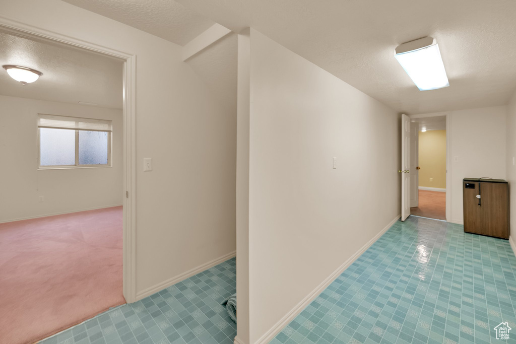 Corridor with carpet floors, baseboards, and a textured ceiling