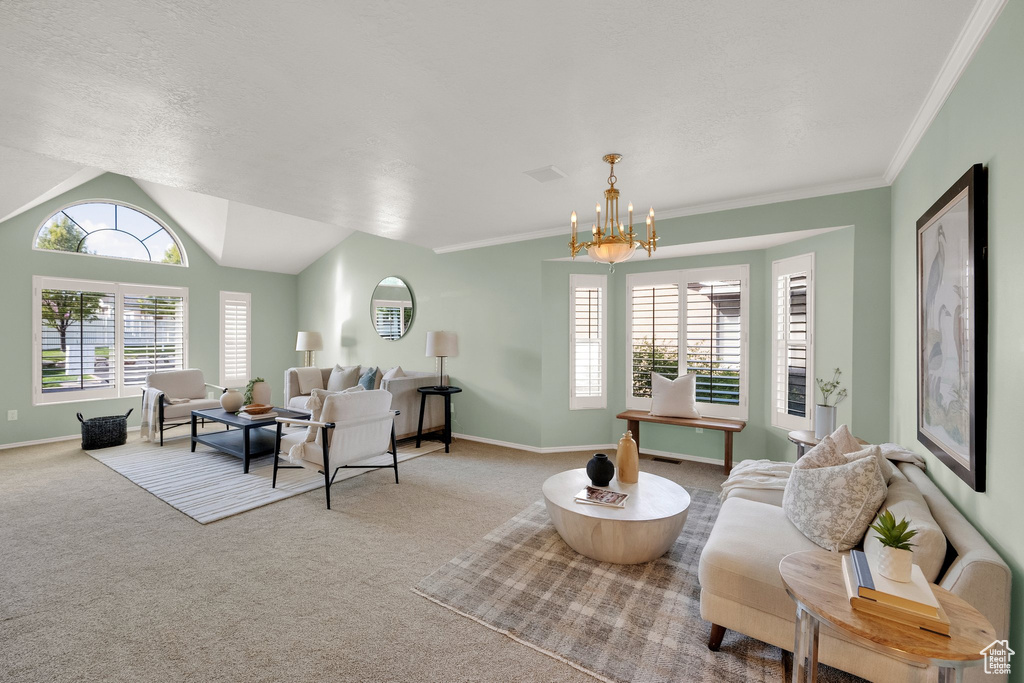 Carpeted living area with baseboards, crown molding, a notable chandelier, and vaulted ceiling