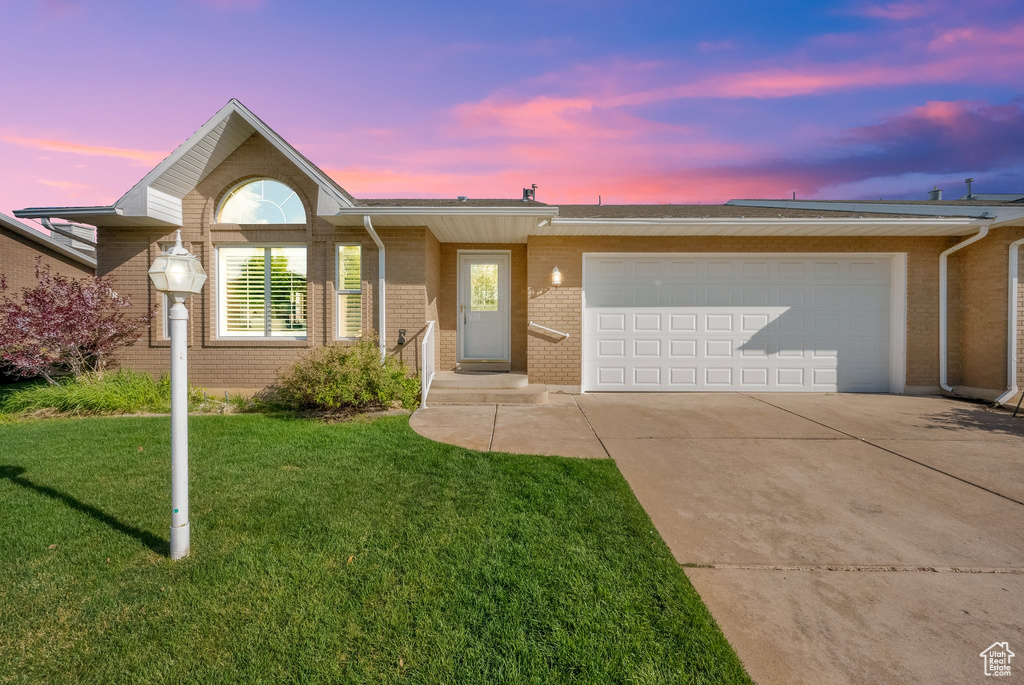 Single story home with a garage, a lawn, concrete driveway, and brick siding