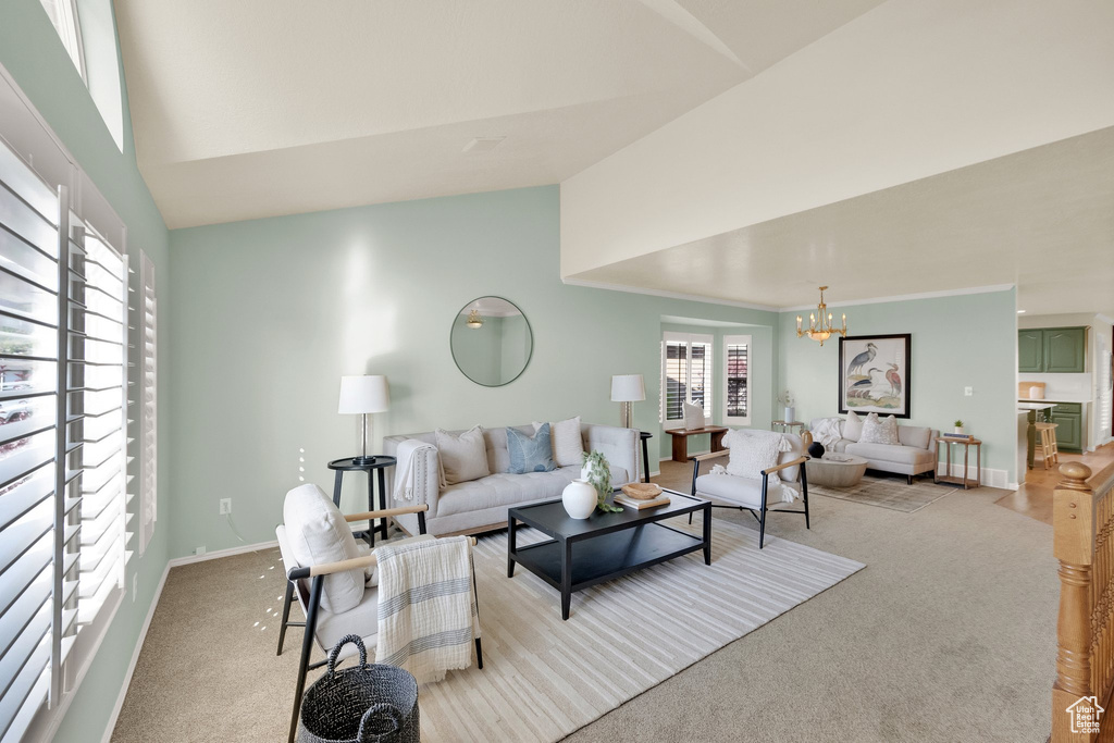 Living room featuring an inviting chandelier, high vaulted ceiling, baseboards, and light carpet