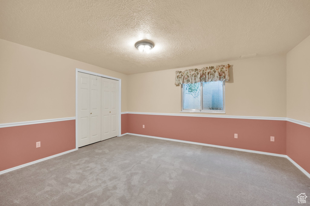 Unfurnished bedroom featuring a closet, carpet, a textured ceiling, and baseboards