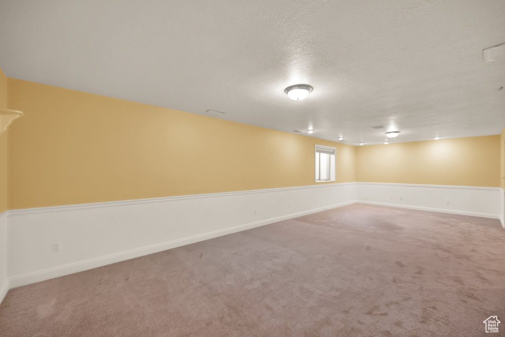 Basement with carpet floors, a textured ceiling, and baseboards