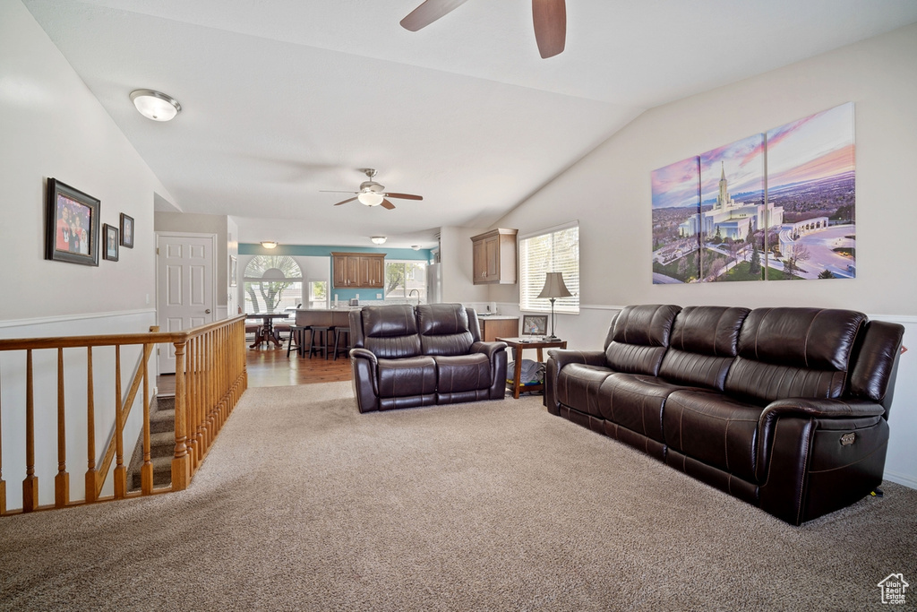 Living area featuring lofted ceiling, ceiling fan, and light carpet