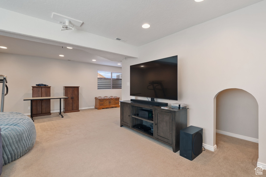Living room with arched walkways, visible vents, light colored carpet, and recessed lighting