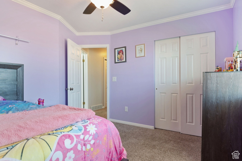Bedroom with carpet, visible vents, a ceiling fan, ornamental molding, and a closet